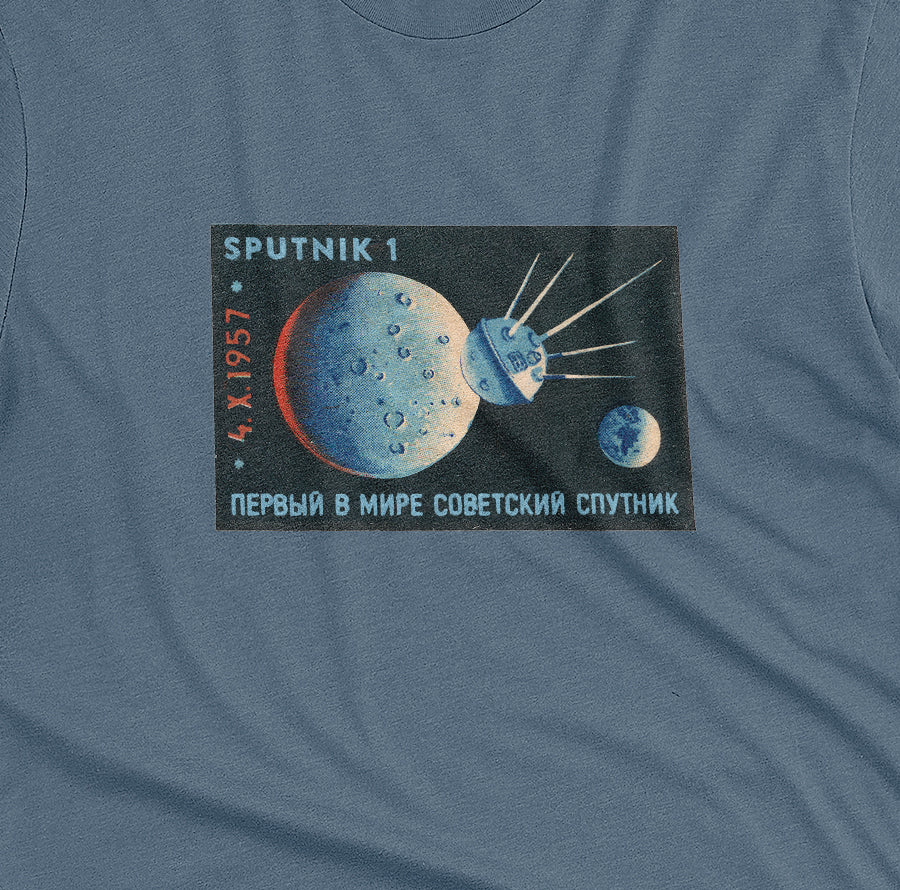 A blue t-shirt with a vintage matchbook illustration celebrating the launch of the first Sputnik satellite.
