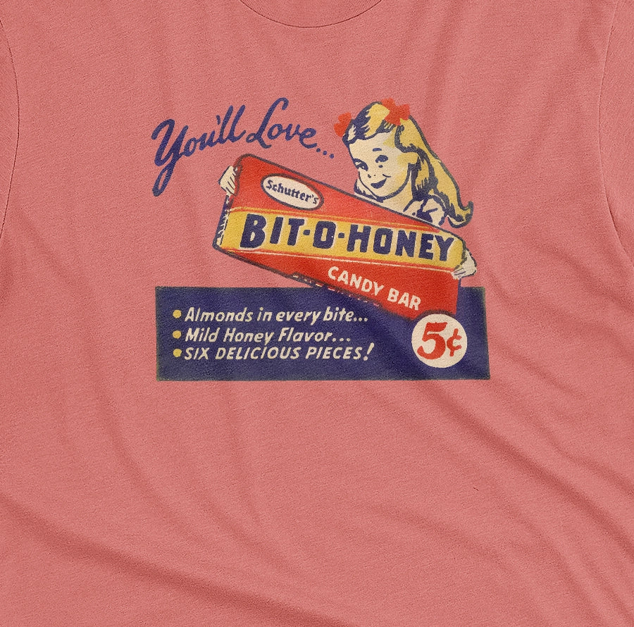 A coral pink t-shirt with a vintage advertisement for the Bit-O-Honey candy bar from the 1960s.