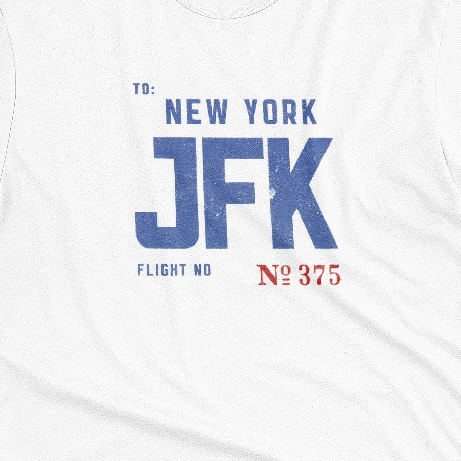 A white t-shirt with a vintage bag tag graphic from the 1960s saying New York JFK.