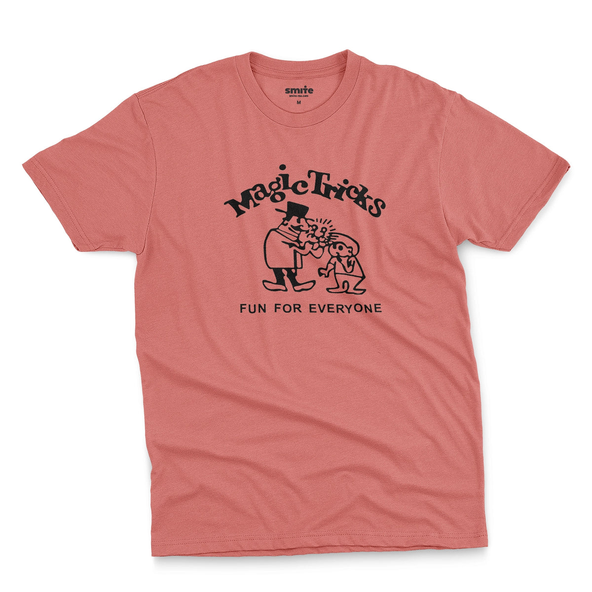 A coral pink t-shirt with a black graphic print on the front that reads 'Magic Tricks' above a cartoon of a magician and a spectator, with 'FUN FOR EVERYONE' printed below.