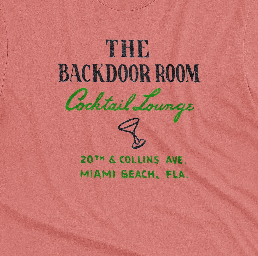 A coral pink t-shirt with a retro advertisement for 'THE BACKDOOR ROOM Cocktail Lounge' on Miami Beach, Florida.