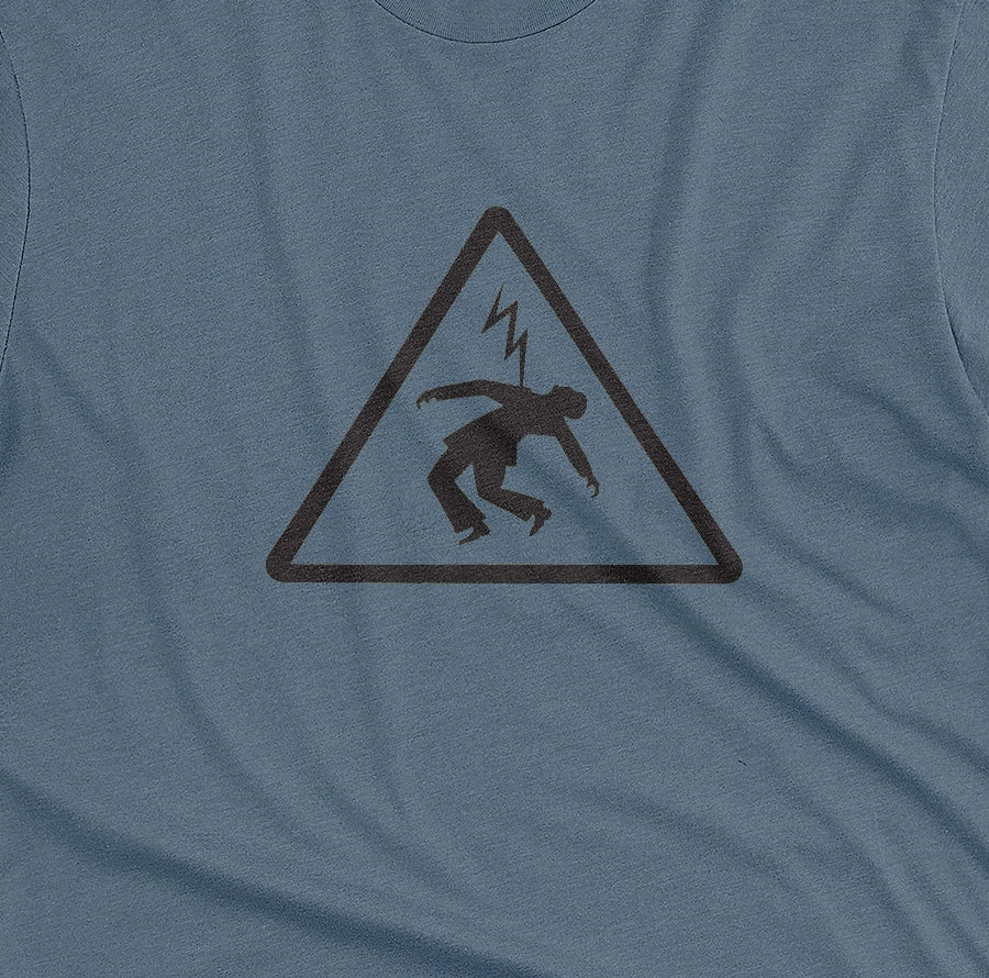 A blue t-shirt with an old Spanish sign on it, warning of the danger of electrocution.