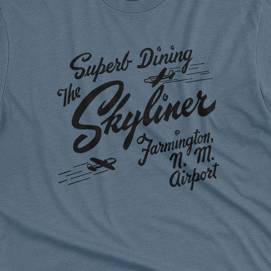 A blue t-shirt with a retro advertisement for The Skyliner restaurant at the airport in Farmington, New Mexico.