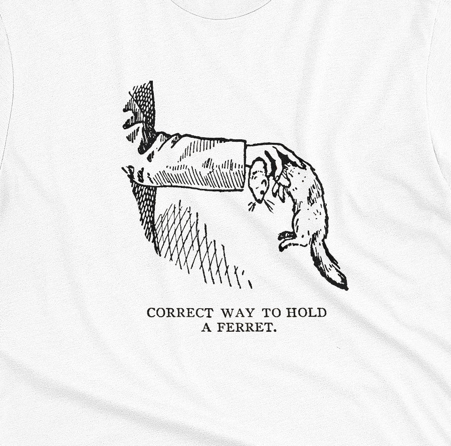 A white t-shirt with a vintage engraved illustration of an arm holding a ferret and text saying: Correct way to hold a ferret.