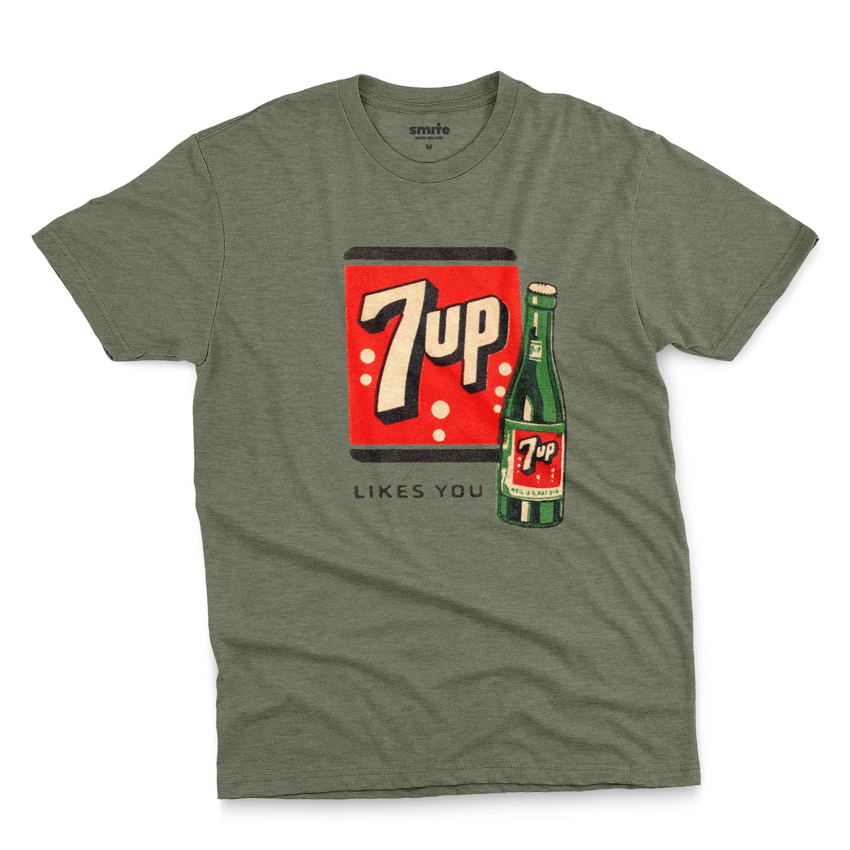A green t-shirt featuring a retro advertisement for 7up with the text '7up LIKES YOU'.