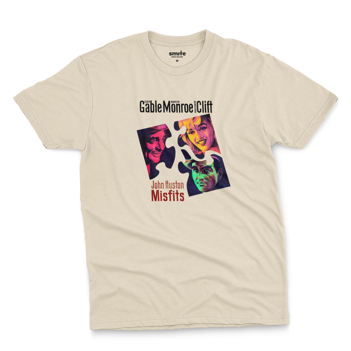 A beige t-shirt featuring a colorful graphic advertisement for the movie The Misfits starring Clark Gable, Marilyn Monroe, and Montgomery Clift.