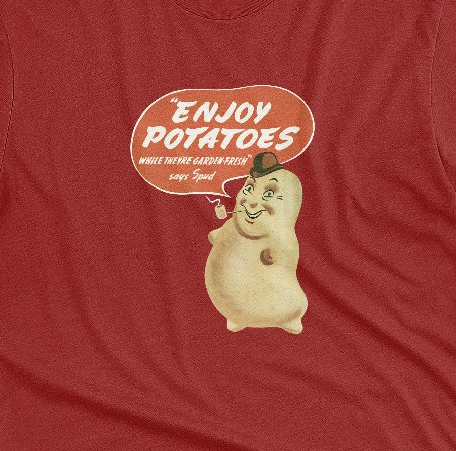 A red t-shirt with a vintage graphic of a smiling potato character and a speech bubble that reads 'ENJOY POTATOES'.