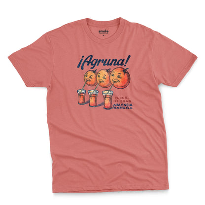 A coral pink t-shirt with a graphic print of Agruna brand fruit crate art from Valencia, Spain in the early 1900's.