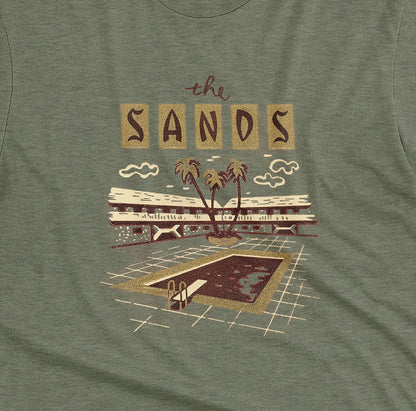 A green t-shirt with a retro advertisement for 'the SANDS' hotel featuring a poolside scene.