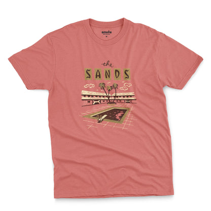 A coral pink t-shirt with a retro advertisement for 'the SANDS' hotel featuring a poolside scene.