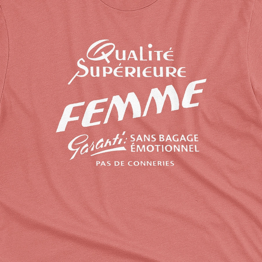 A coral pink t-shirt with white French text printed on the front. It translates as 'Superior Quality Woman Guarantee: No Emotional Baggage'.