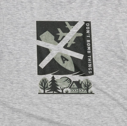 A grey marle t-shirt with a retro graphic print of an anti-war message featuring a cross, a plane, a house, and the text 'DON'T BOMB THINGS'.