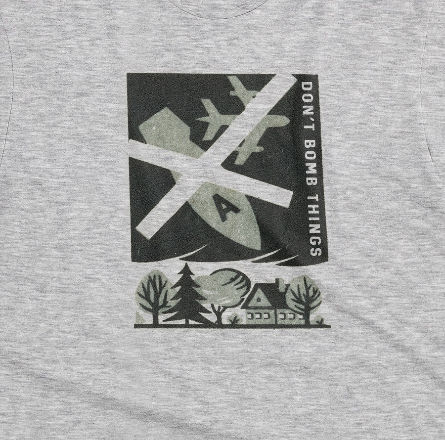 A grey marle t-shirt with a retro graphic print of an anti-war message featuring a cross, a plane, a house, and the text 'DON'T BOMB THINGS'.