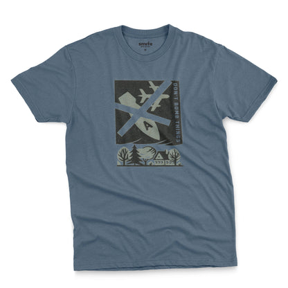 A blue t-shirt with a retro graphic print of an anti-war message featuring a cross, a plane, a house, and the text 'DON'T BOMB THINGS'.
