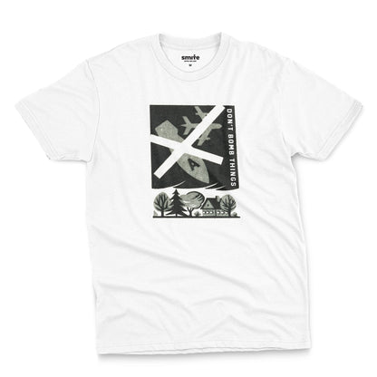 A white t-shirt with a retro graphic print of an anti-war message featuring a cross, a plane, a house, and the text 'DON'T BOMB THINGS'.