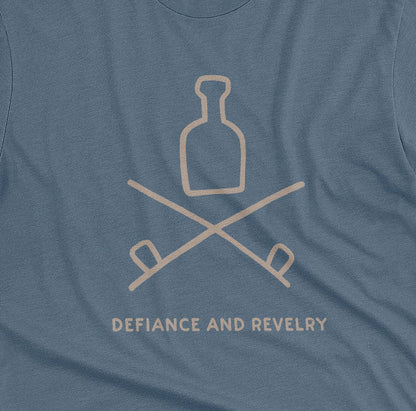 A blue t-shirt with a grey graphic of a bottle and crossed smoking pipes beneath it and the words defiance and revelry. The graphic is from an 1800s Australian convict tattoo.