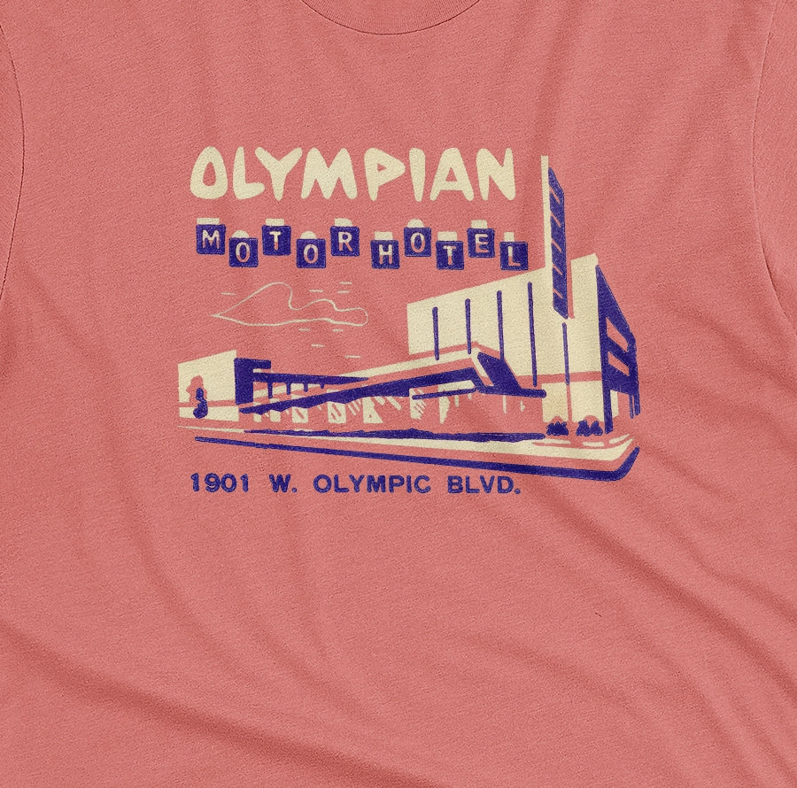 A coral pink t-shirt with a vintage advertisement for the Olympian Motor Hotel.