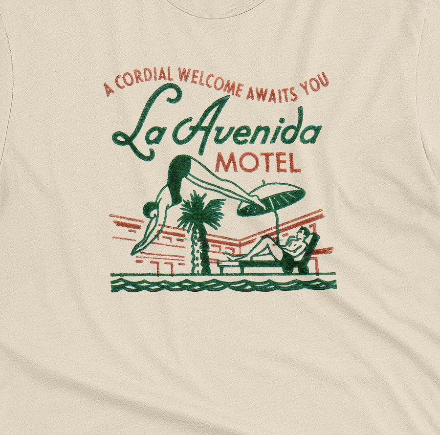 A beige t-shirt featuring a retro advertisement for La Avenida Motel from the 1960s.