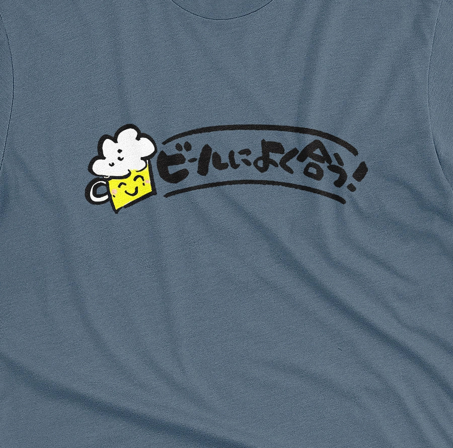 A blue t-shirt featuring a cartoon-style graphic of  a jug of beer and the Japanese text 'Great With Beer!' in black.