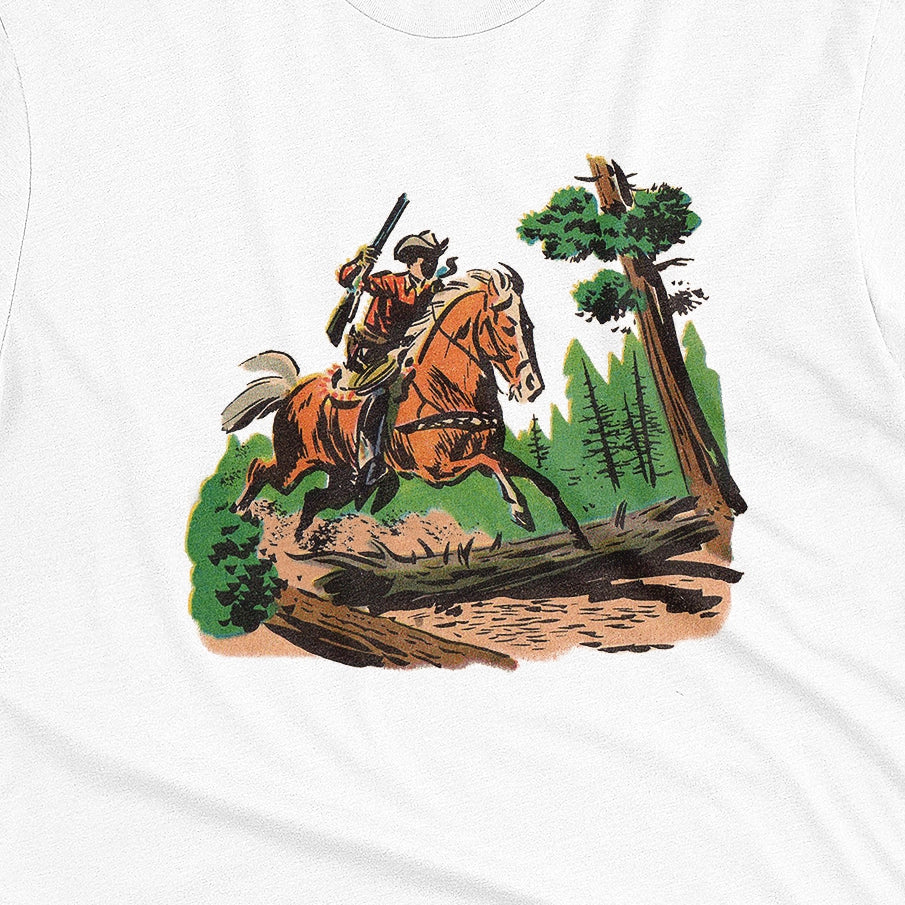 A white t-shirt featuring a 1960s vintage graphic print of a cowboy riding a horse through a forest.