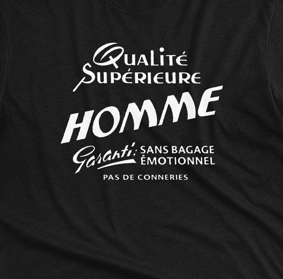 A black t-shirt with white French text printed on the front. It translates as 'Superior Quality Man Guarantee: No Emotional Baggage'.
