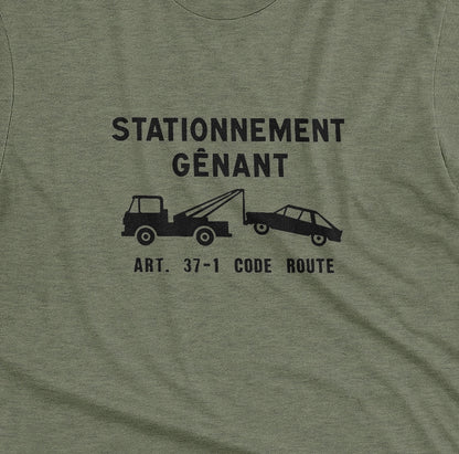 A green t-shirt with a graphic print of a French street sign that says "nuisance parking" in French and a picture of a car being towed away.