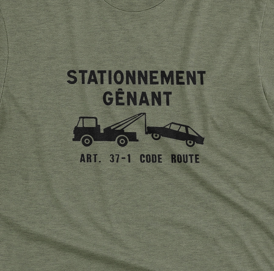 A green t-shirt with a graphic print of a French street sign that says "nuisance parking" in French and a picture of a car being towed away.