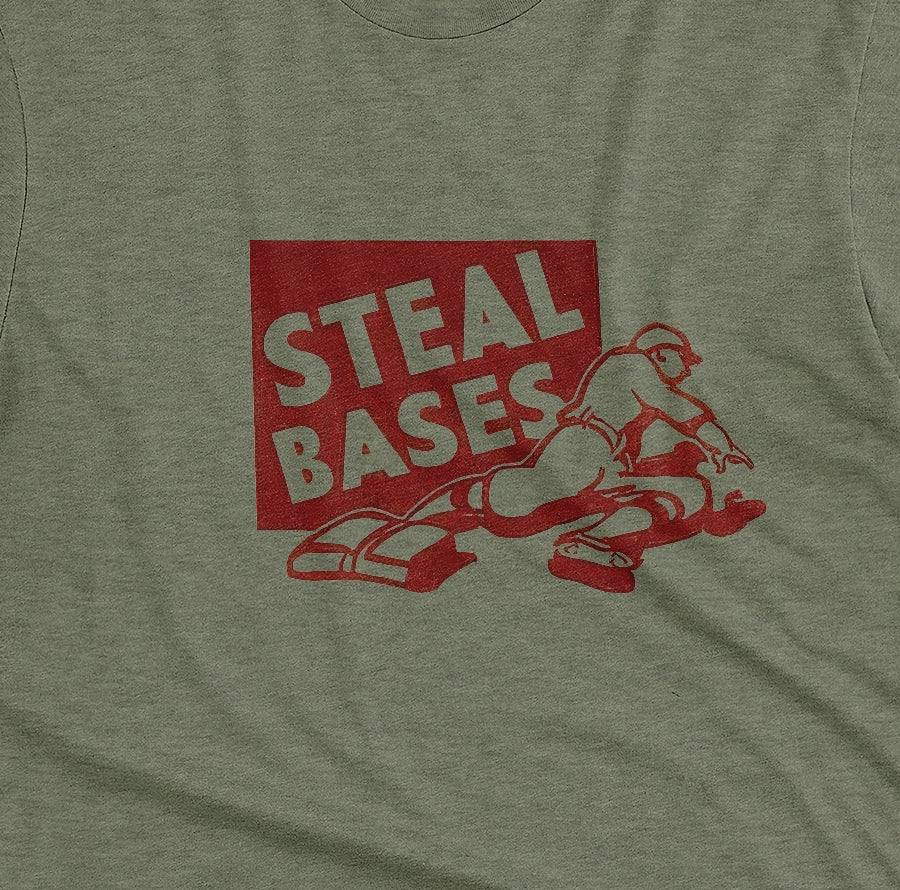 A green t-shirt featuring a retro graphic featuring an illustration of a baseball player and the text 'STEAL BASES'.