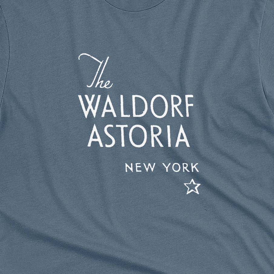 A blue t-shirt with a retro logo for The Waldorf Astoria hotel in New York.