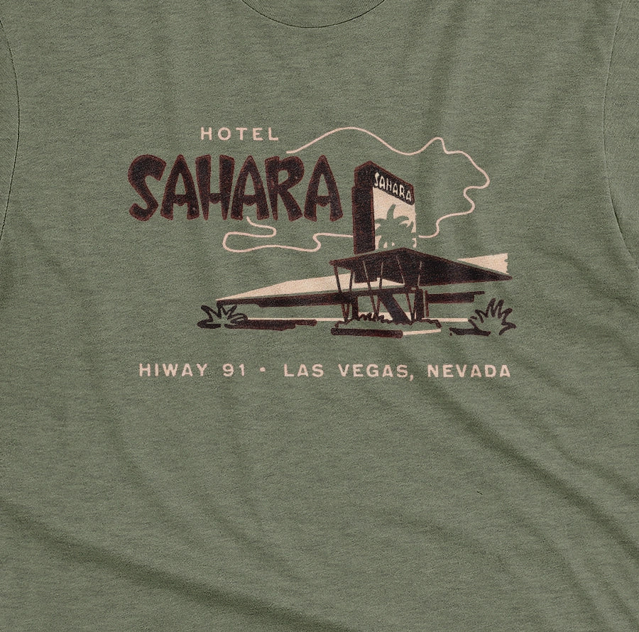 A green t-shirt with a vintage graphic advertising the 'Hotel Sahara' in Las Vegas, Nevada.