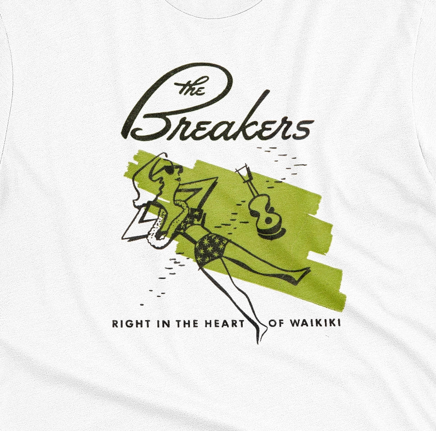 A white t-shirt featuring a retro illustration of a woman sunbathing, advertising The Breakers, a Hawaiian hotel.