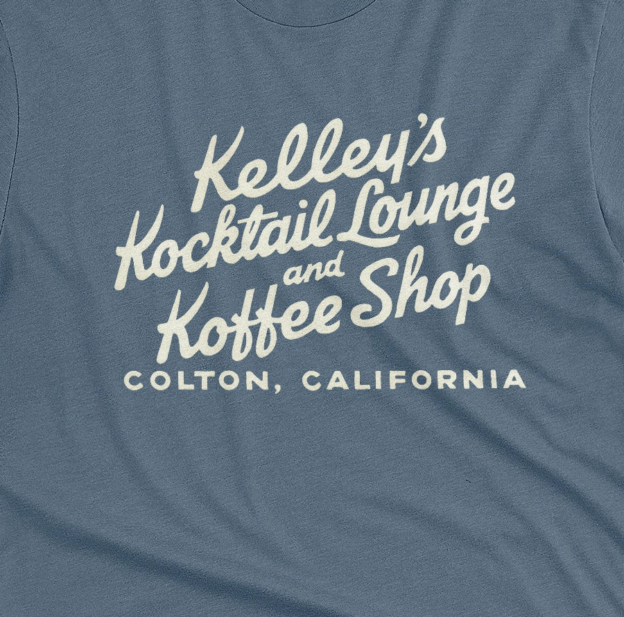 A blue t-shirt with a retro typographic advertisement for Kelley's Kocktail Lounge and Koffee Shop in Colton, California.