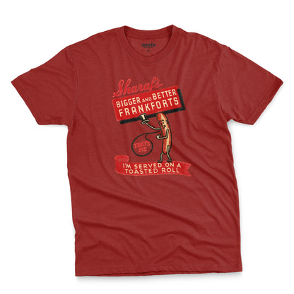A red t-shirt with a vintage graphic print of a hot dog character holding a sign that reads 'Sharaf's Bigger and Better Frankforts'.