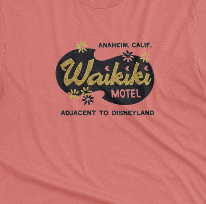 A coral pink t-shirt with a retro advertisement for the 'Waikiki Motel' in Anaheim, California.