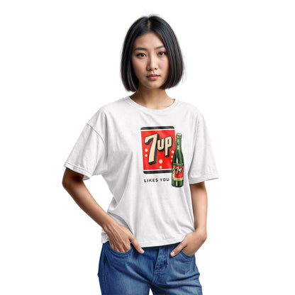A white t-shirt featuring a retro advertisement for 7up with the text '7up LIKES YOU'.