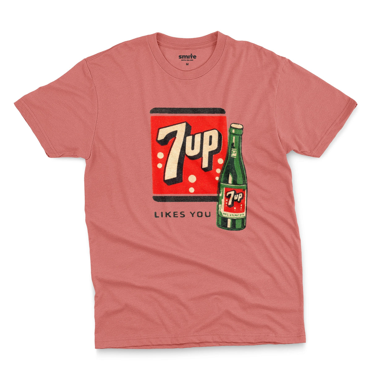 A coral pink t-shirt featuring a retro advertisement for 7up with the text '7up LIKES YOU'.