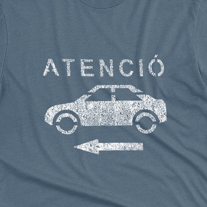 A blue t-shirt with a retro white stencil graphic of a car and the Spanish word 'ATENCIÓ'.