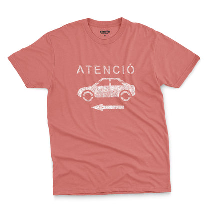 A coral pink t-shirt with a retro white stencil graphic of a car and the Spanish word 'ATENCIÓ'.