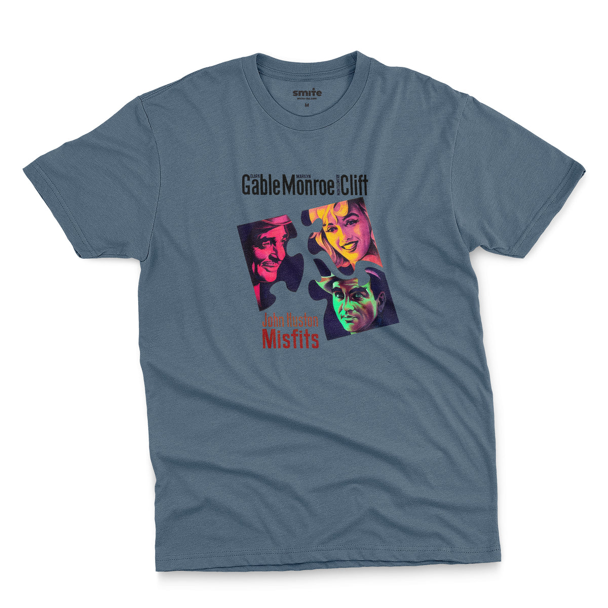 A blue t-shirt featuring a colorful graphic advertisement for the movie The Misfits starring Clark Gable, Marilyn Monroe, and Montgomery Clift.