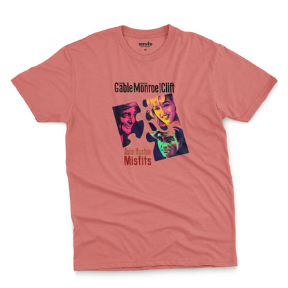 A coral pink t-shirt featuring a colorful graphic advertisement for the movie The Misfits starring Clark Gable, Marilyn Monroe, and Montgomery Clift.
