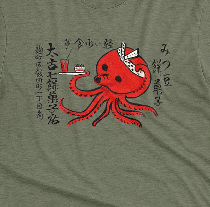 A green t-shirt with an advertisement for Mochi confectionery store featuring an octopus serving food and drink. From Japan in the 1950s.