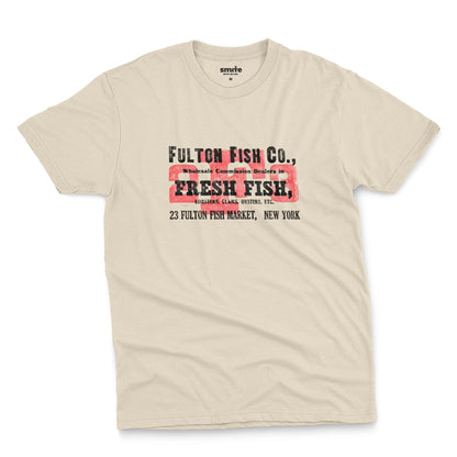 A beige t-shirt with an advertisement for the 'FULTON FISH CO' in New York from the 1970s.
